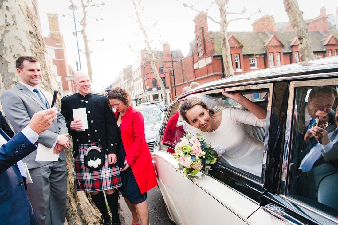 bride reaching out of the wedding car