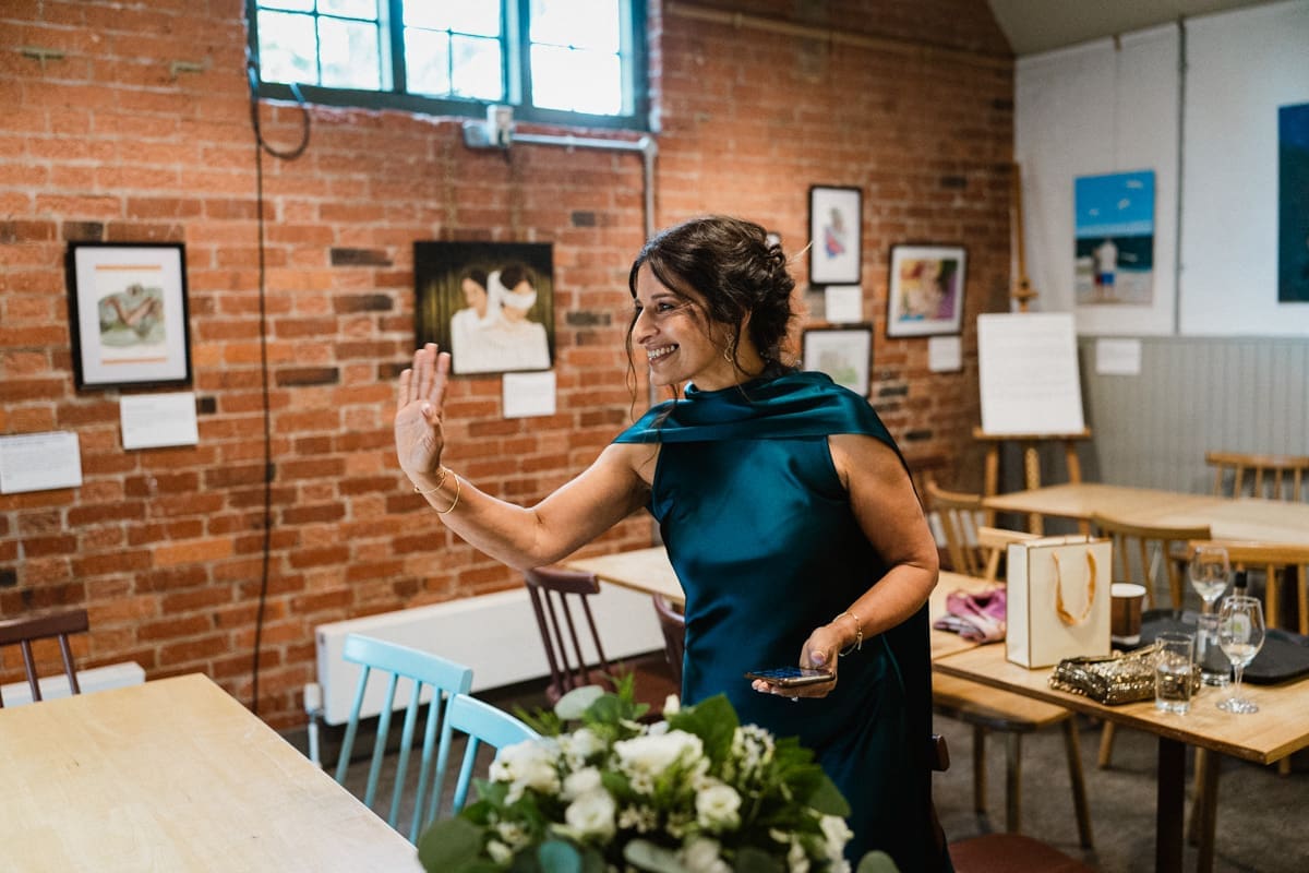 indian bride waves to guests as they arrive at wedding