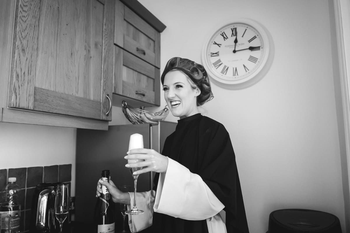 bride pouring champagne while getting ready for her wedding