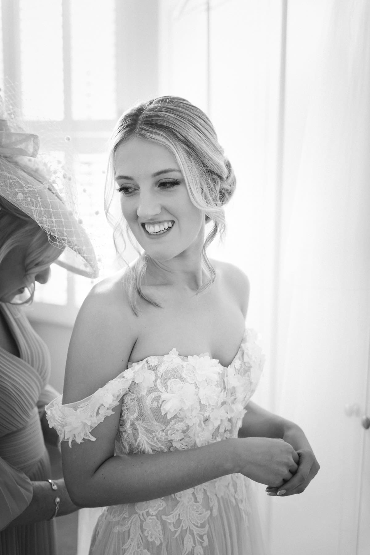 mother of the bride helps button up the wedding dress