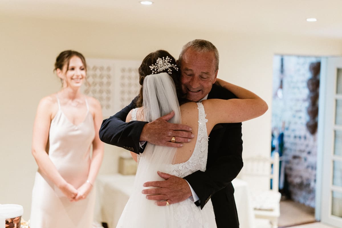father of the bride hugs his daughter on her wedding day