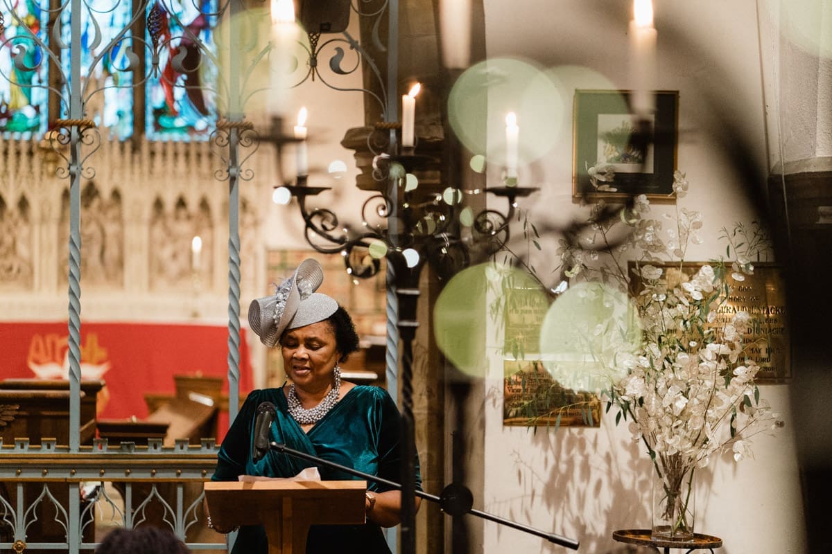 the mother of the groom giving a reading at a church wedding ceremony