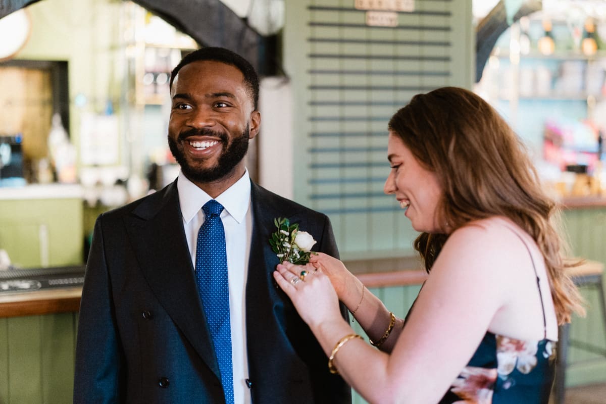 the groom having his buttonhole pinned on