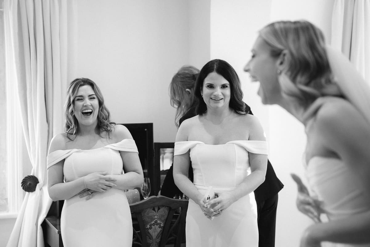black and white photo of the bride sharing a joke with her bridesmaids
